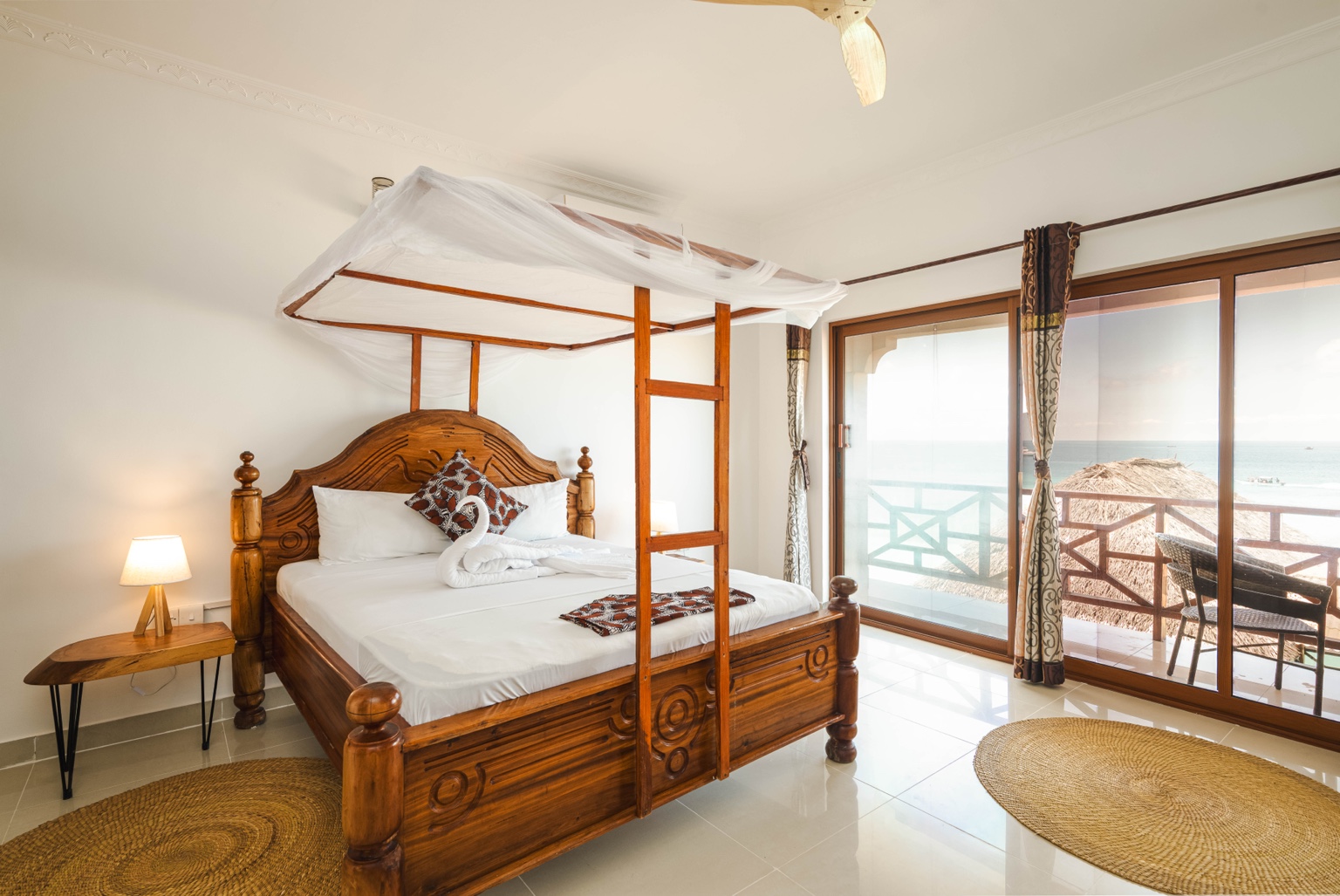 King Suite with Ocean View — Canopy bed beside the ocean-facing windows